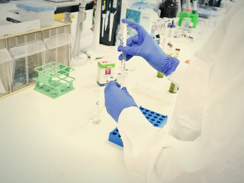 A Bazelet lab technician pipetting samples during formulation testing, with product vials on the bench